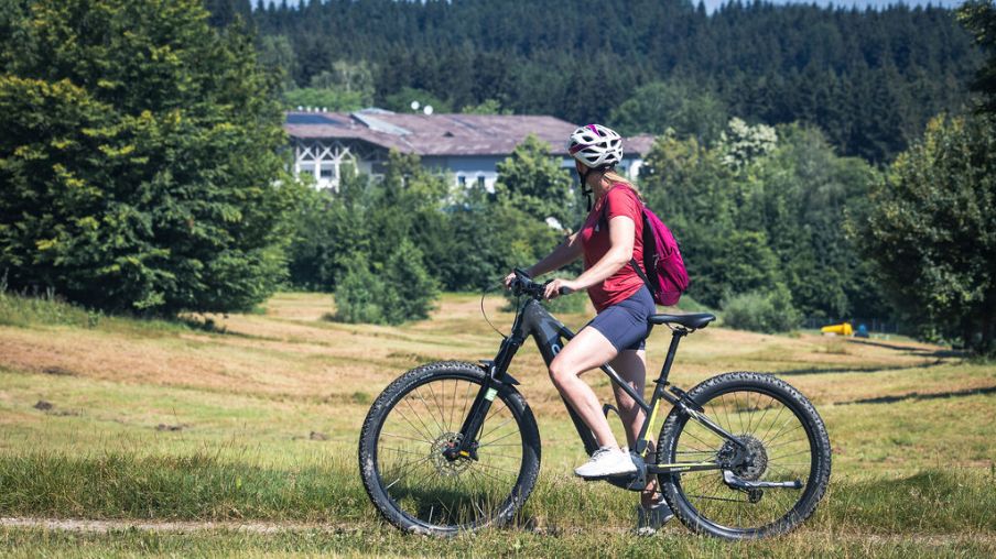 Frau sitzt am Fahrrad und schaut auf den Aldiana Club Ampflwang 