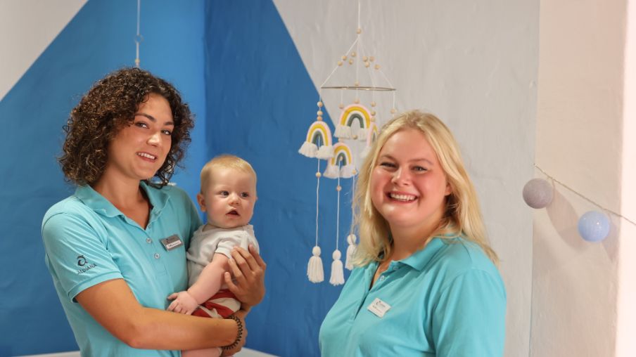 Zwei Personen mit Baby bei der Babybetreuung