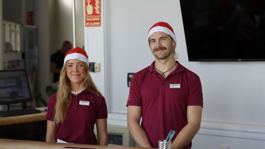 Zwei Personen mit Weihnachtsmütze hinter der Rezeption