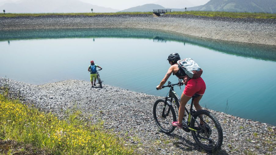 Zwei Menschen auf Fahrrädern vor einem kleinen Bergsee