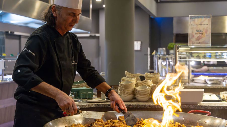 Koch am Buffet mit Flammen und Essen