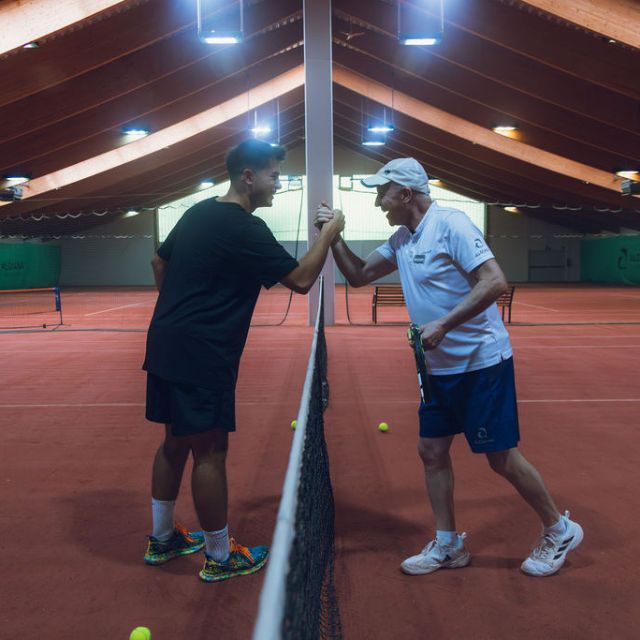 Zwei Männer in der Tennishalle geben sich die Hand 