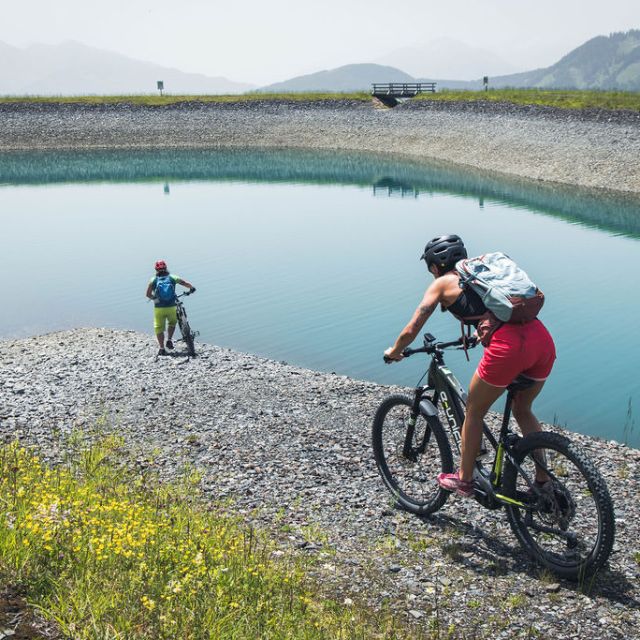 Zwei Menschen auf Fahrrädern vor einem kleinen Bergsee