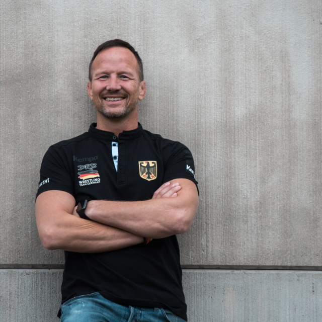 Mann lächelt in die Kamera mit verschränkten Armen