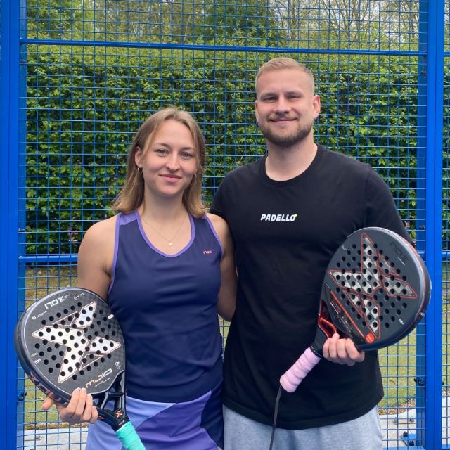 Zwei Personen lächeln in die Kamera mit Padel Schläger