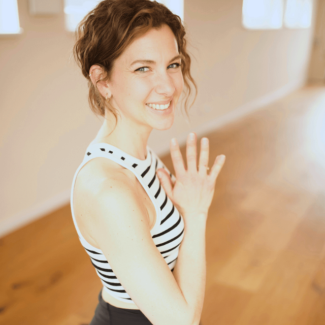 Frau lächelt in die Kamera und macht eine Yoga Pose