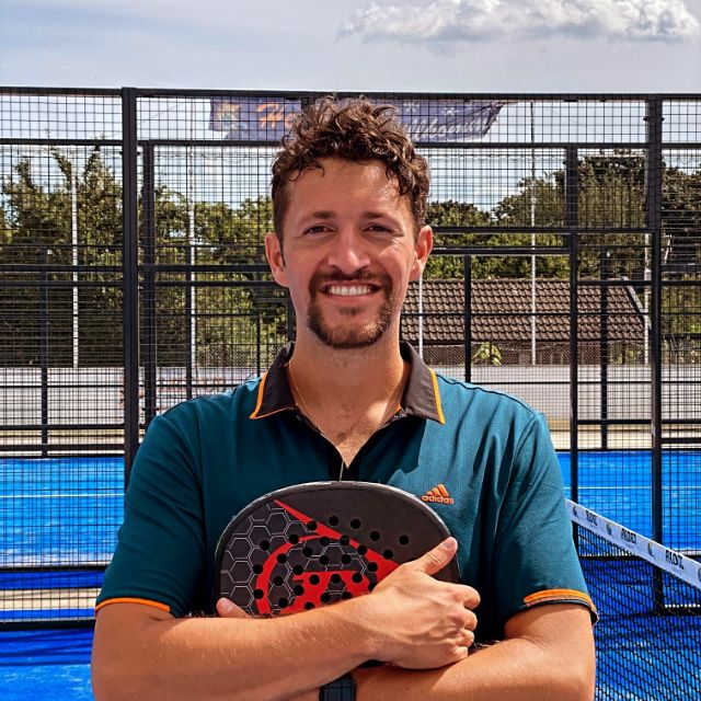 Mann lächelt in die Kamera und hält einen Padel Schläger in der Hand