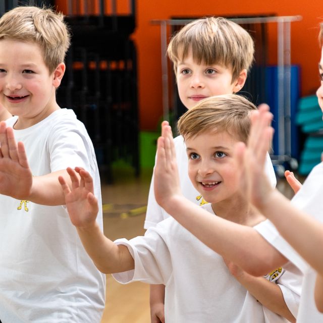 Kinder lachen und machen eine Karate Bewegung 