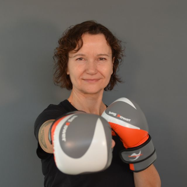 Frau lächelt in die Kamera mit Boxhandschuhen
