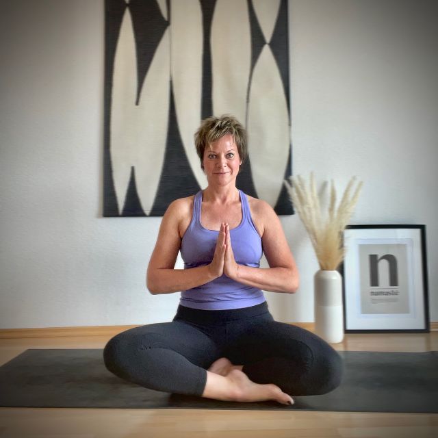 Frau sitzt am Boden und macht Yoga