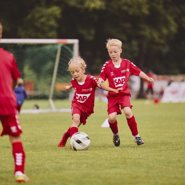 Kinder spielen Fußball und versuchen einen Ball abzunehmen 
