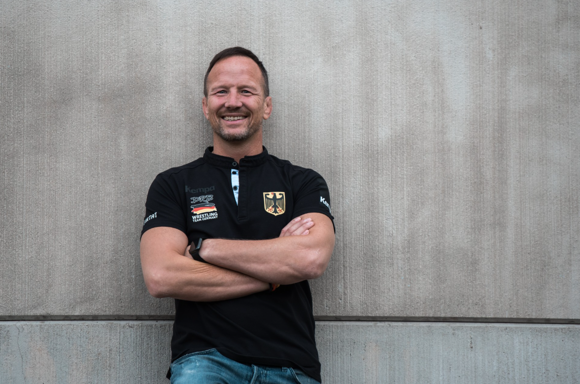 Mann lächelt in die Kamera mit verschränkten Armen
